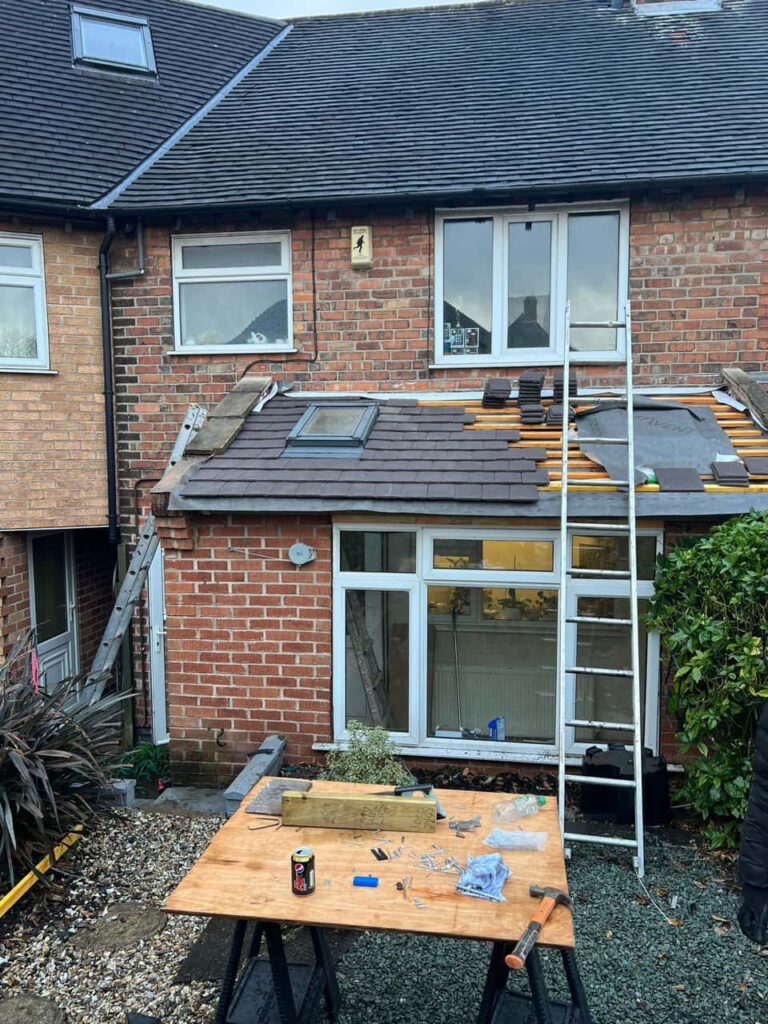 This is a photo of a roof extension that is having new roof tiles installed. This is a photo taken from the roof ridge looking down a tiled pitched roof on to a flat roof. Works carried out by Cottenham Roofing Repairs