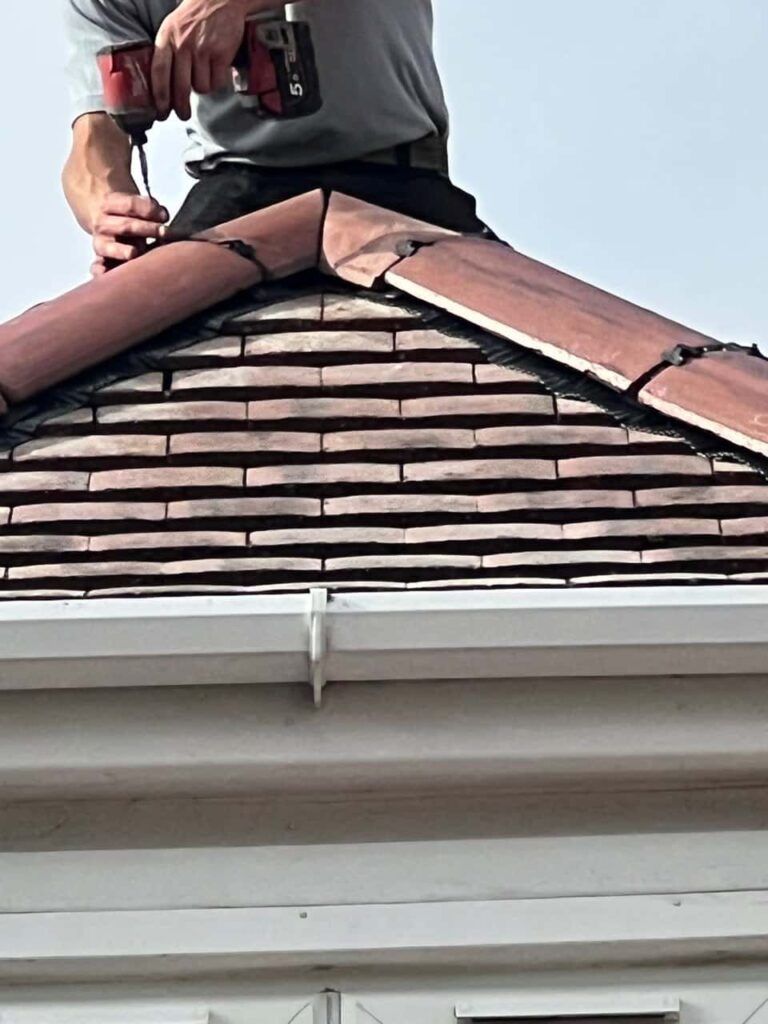 This is a photo of one of the operatives of Cottenham Roofing Repairs installing new ridge tiles