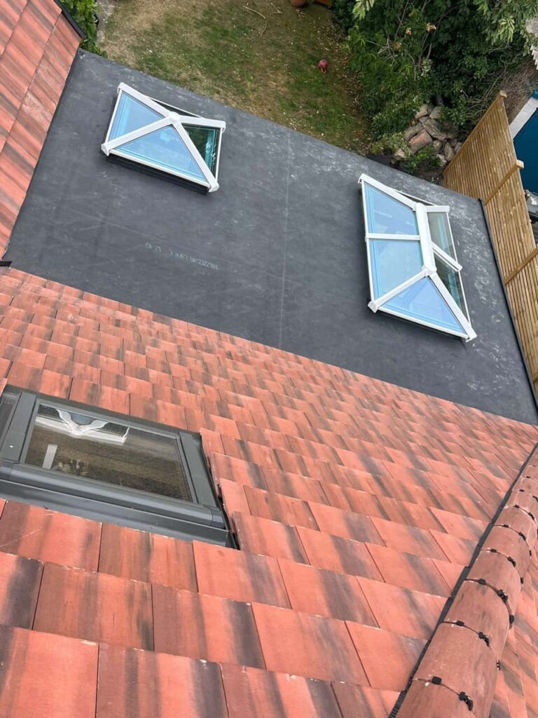 This is a photo taken from the roof ridge looking down a tiled pitched roof on to a flat roof. Works carried out by Cottenham Roofing Repairs